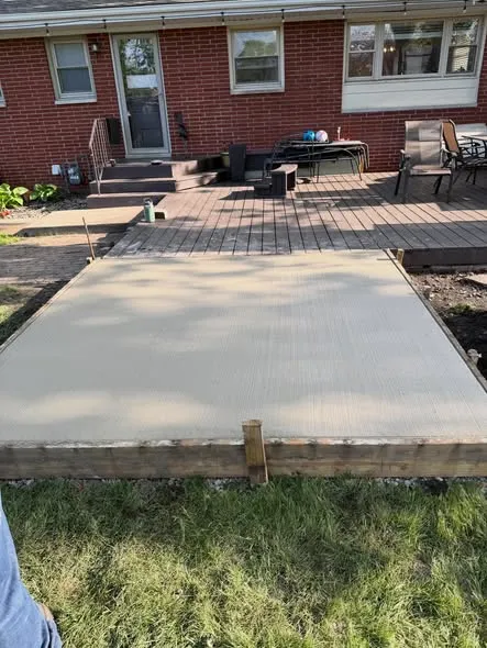 Freshly poured concrete patio behind a brick home